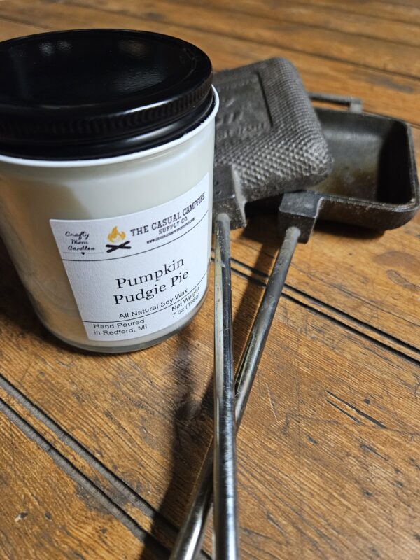 A pumpkin scented candle sits next to a cast iron campfire pie maker.